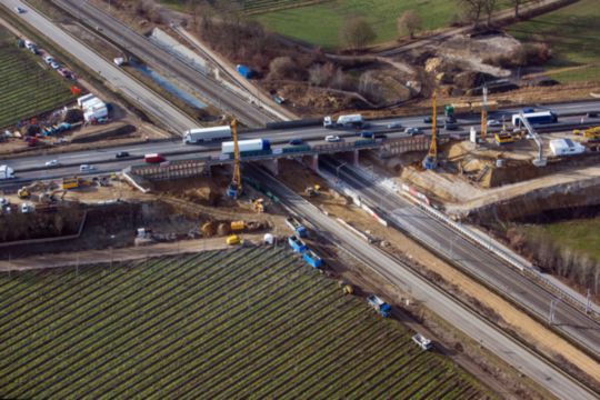 Zeigt einen Bagger bei der Arbeit an Bahnschienen